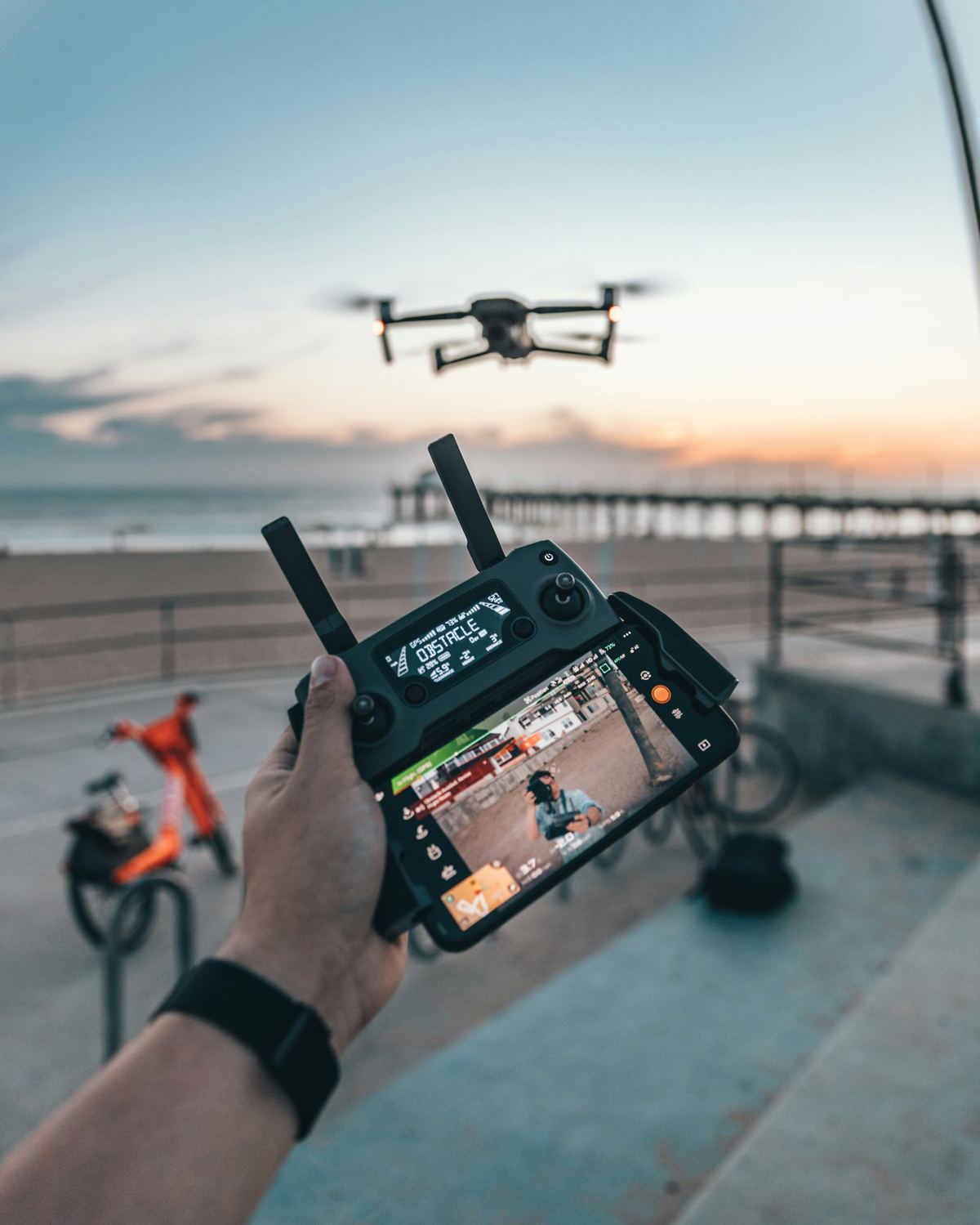 A drone pilot flying a mission at sunset, reviewing live telemetry on the controller